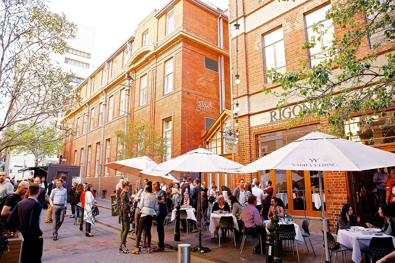 People milling about drinking wine outside a restaurant in an activated laneway